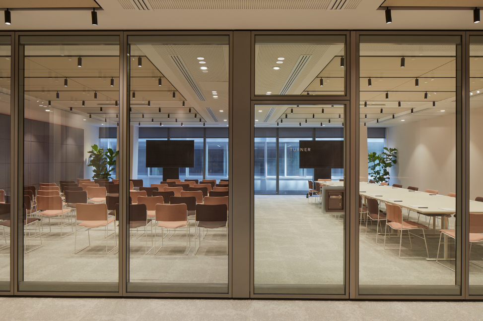 One of the meeting rooms in Myo St Paul's offices, converted to facilitate a presentation, with rows of audience seating and large screens.