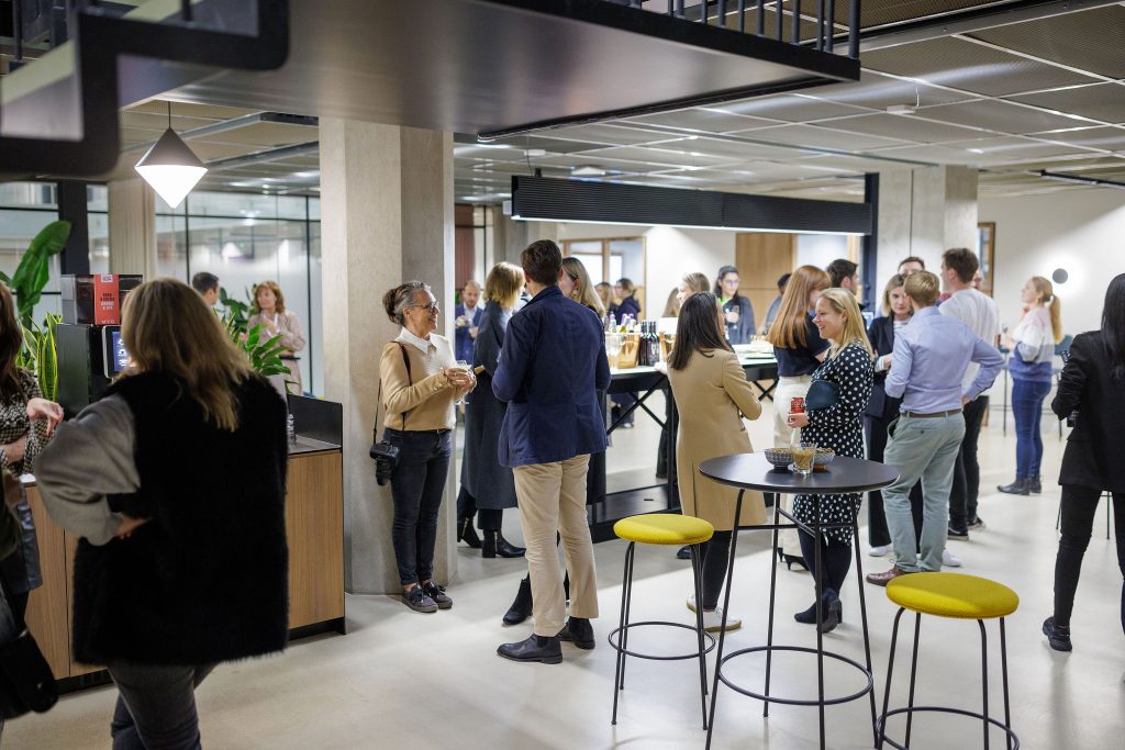 A group of people mingle in the shared space at Myo's Victoria Street office.