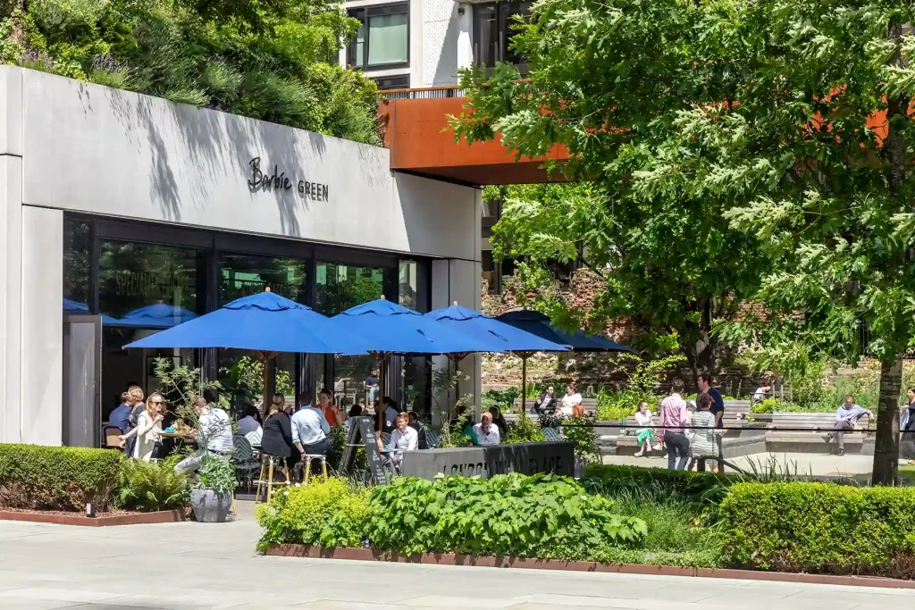 An outdoor seating area with greenery and umbrellas for shade.