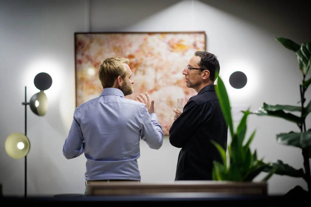 Office professionals discussing art in front of a colourful painting.